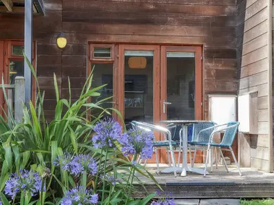 a porch with a table and chairs and purple flowers at Tehidy in Truro