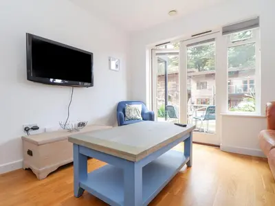 a living room with a table and a tv on the wall at Tehidy in Truro