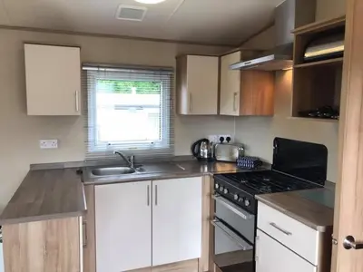 a kitchen with white cabinets and a stove top oven at Newquay Cornwall Holiday Rental in Newquay