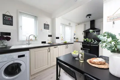 a kitchen with a washer and dryer and a table at Sunshine Cottage, Padstow in Padstow
