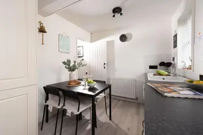 a white kitchen with a black table and chairs at Sunshine Cottage, Padstow in Padstow