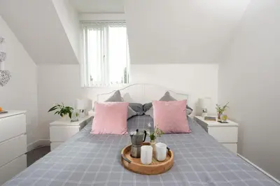 a bedroom with a large bed with pink pillows at Sunshine Cottage, Padstow in Padstow