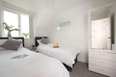 a bedroom with two beds and a mirror at Sunshine Cottage, Padstow in Padstow
