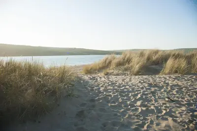 a sandy beach next to a body of water at Sunshine Cottage, Padstow in Padstow