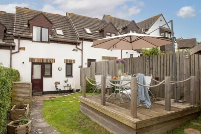 a wooden deck with a table and an umbrella at Sunshine Cottage, Padstow in Padstow