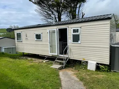 a mobile home with its door open in a yard at 93 Newquay Bay resort Pet friendly in Newquay