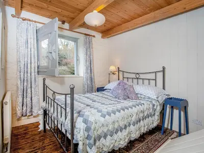 a bedroom with a bed and a window at Hallowarren Barn in Saint Anthony