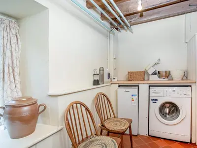 a kitchen with a washing machine and two chairs at Hallowarren Barn in Saint Anthony