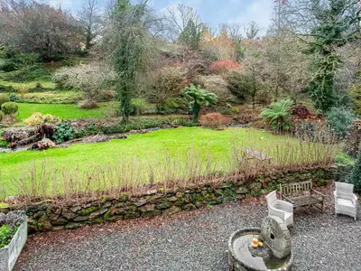 a garden with two benches and a stone wall at Hallowarren Barn in Saint Anthony