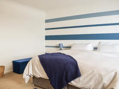 a bedroom with a bed with blue and white stripes at The Dawn in Looe
