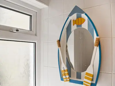 a bathroom with a surfboard mirror on the wall at The Dawn in Looe