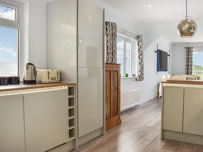 a kitchen with white walls and wooden floors at The Dawn in Looe