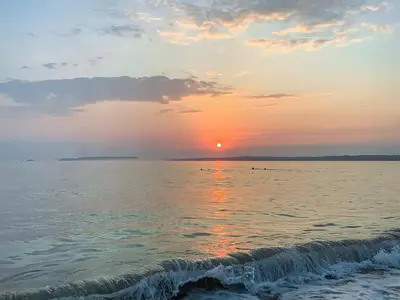 a sunset over the ocean with a wave at The Lodge in Uny Lelant