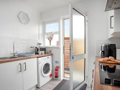 a white kitchen with a washing machine in it at Number One in Saint Dennis