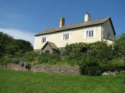 an old house on a hill with a stone wall at Woodgate in Bude