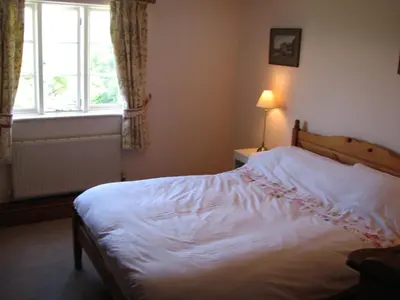 a bedroom with a white bed with a window at Woodgate in Bude