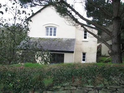 a white house with a tree in front of it at Woodgate in Bude