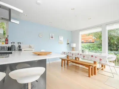 a white kitchen with a table and chairs and a window at 9 Cedars in St. Agnes