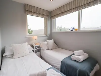 two beds in a room with two windows at 9 Cedars in St. Agnes