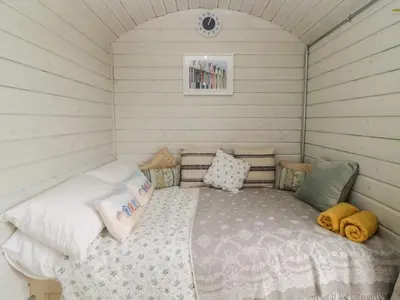 a small room with a bed with pillows at Flora's Hut in Liskeard