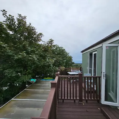 a balcony of a house with a patio and trees at Goonearl Simply Stay in Scorrier