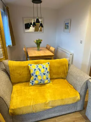 a yellow couch with a pillow on it in a living room at Citrus Chalet in Redruth