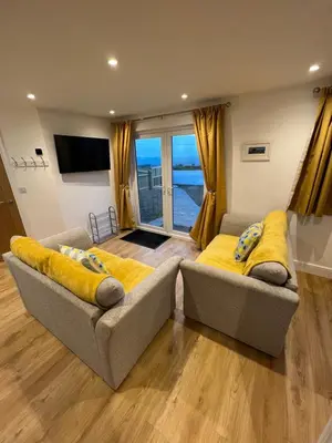 a living room with two couches and a large window at Citrus Chalet in Redruth