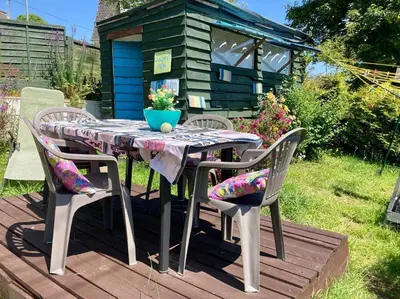 a table and chairs on a deck with a house at Guest house Truro garden retreat in Kenwyn