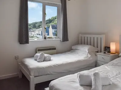 two beds in a room with a window at Merizac in Budock Water