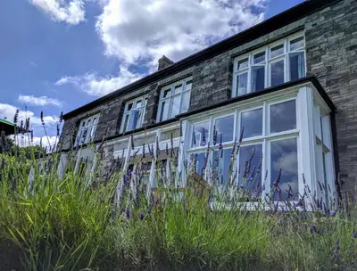 a brick house with white windows and tall grass at Costislost House in Wadebridge
