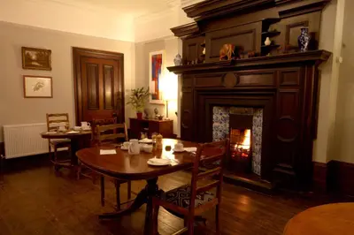 a dining room with a table and a fireplace at Costislost House in Wadebridge