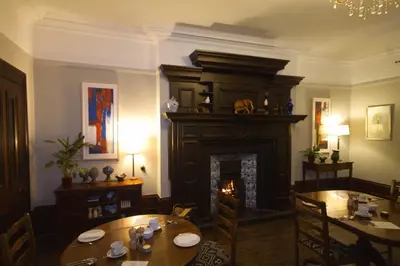 a dining room with a fireplace and a table and chairs at Costislost House in Wadebridge
