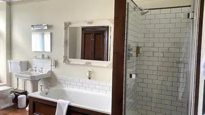 a bathroom with a tub and a sink and a mirror at Costislost House in Wadebridge