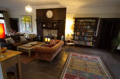 a living room with a couch and a fireplace with a clock at Costislost House in Wadebridge