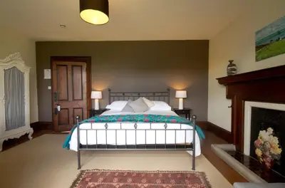 a bedroom with a bed and a fireplace at Costislost House in Wadebridge