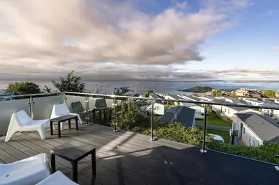 a balcony with white chairs and a view of the ocean at Lanyon in St Ives