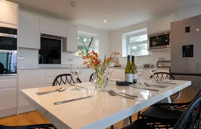a white kitchen with a table with wine glasses at Lanyon in St Ives