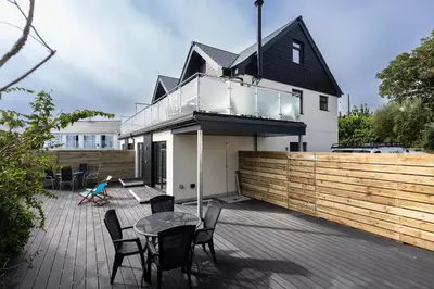 a house with a deck with a table and chairs at Lanyon in St Ives