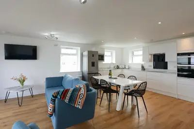 a kitchen and living room with a blue couch and a table at Treen in St Ives