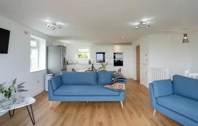 a living room with two blue couches and a kitchen at Treen in St Ives