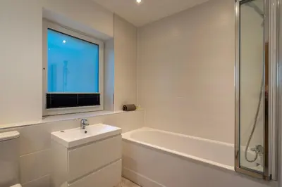 a white bathroom with a sink and a bath tub at Treen in St Ives