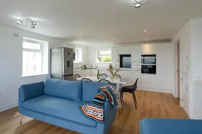 a living room with a blue couch and a kitchen at Treen in St Ives