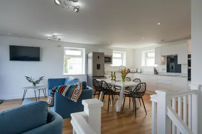 a kitchen and living room with a table and chairs at Treen in St Ives