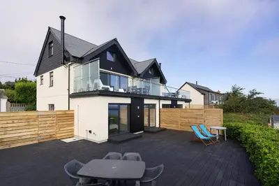 a house with a deck with chairs on a patio at Treen in St Ives