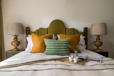 a bed with orange and green pillows and two lamps at Mabyn in Porth