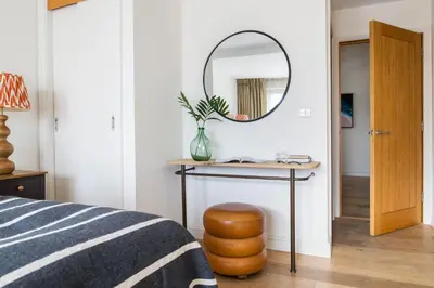 a bedroom with a mirror and a table with a stool at Mabyn in Porth
