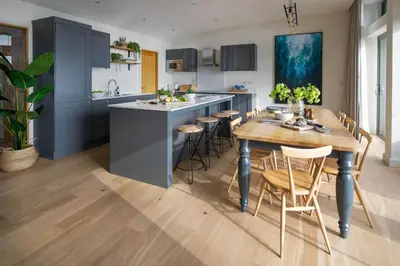 a kitchen with blue cabinets and a wooden table at Mabyn in Porth