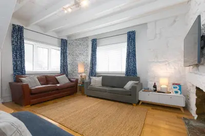 a living room with two couches and a stone wall at Floyd's in St Ives