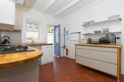 a kitchen with white appliances and a brown tile floor at Floyd's in St Ives