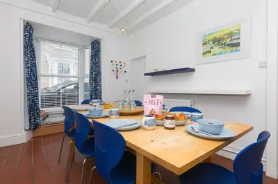 a dining room with a wooden table and blue chairs at Floyd's in St Ives